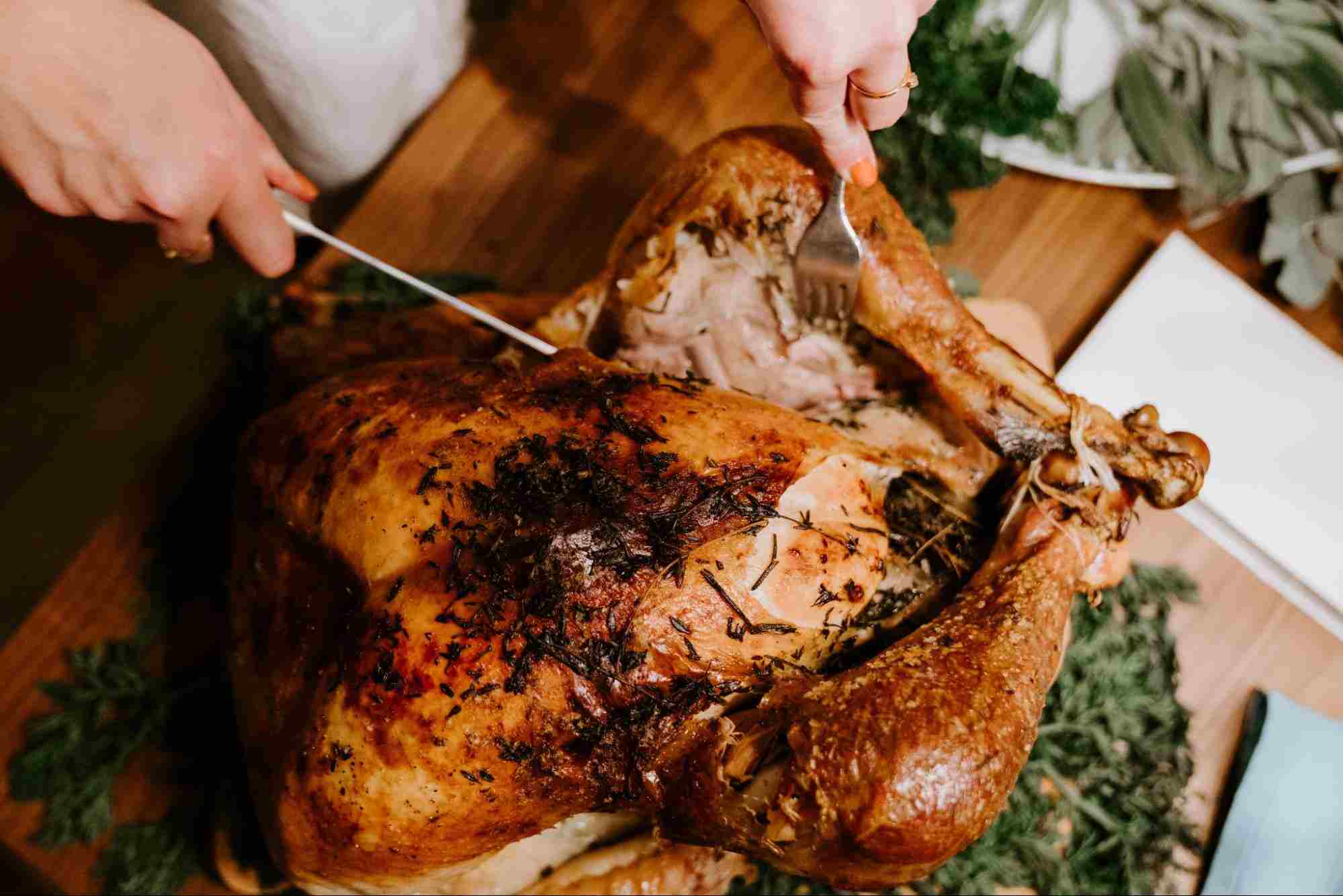 Hands Carving a Turkey With Knife and Carving Fork