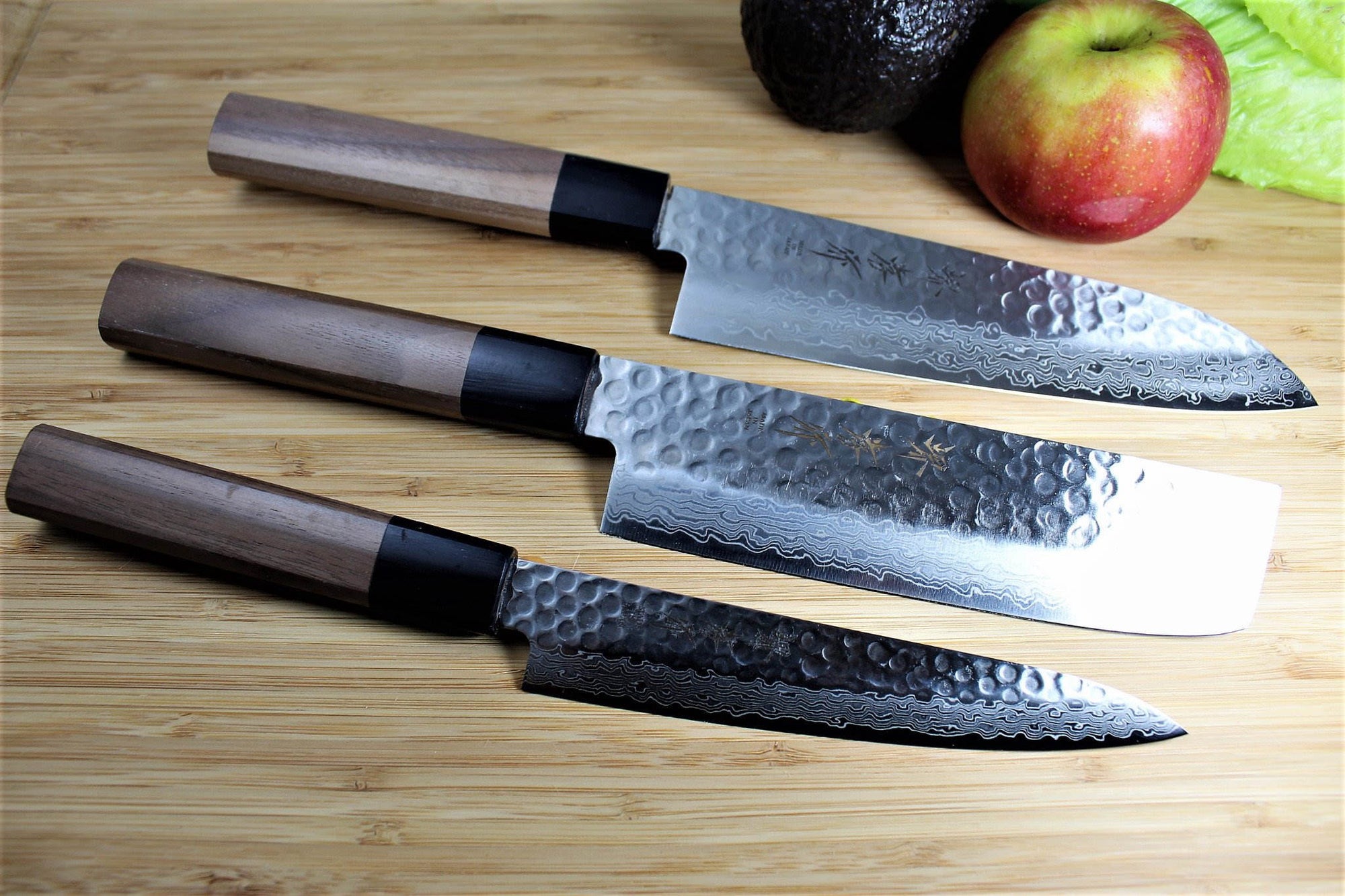 Gyuto Nakiri and petty Japanese kitchen knives stainless steel on cutting board with apple