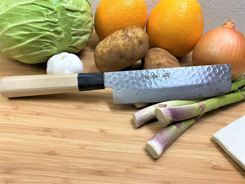 Artisan japanese knife on a cutting board with spinach and garlic