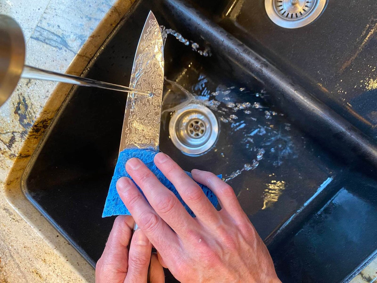 Person handwashing a Japanese knife in the sink