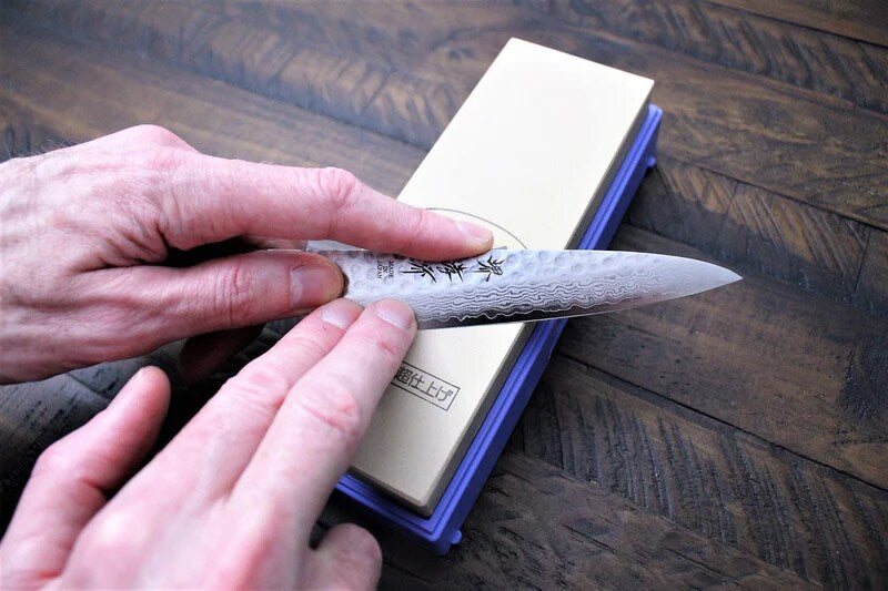 Hands-sharpening-a-Japanese-knife-on-a-whetstone